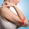 Joint inflammation indicated with red spot on female's elbow. Arm pain and injury concept. Closeup cropped portrait woman with painful elbow isolated on blue background
